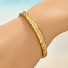 Model wearing a slim gold striped bangle with clear cubic zirconia accents