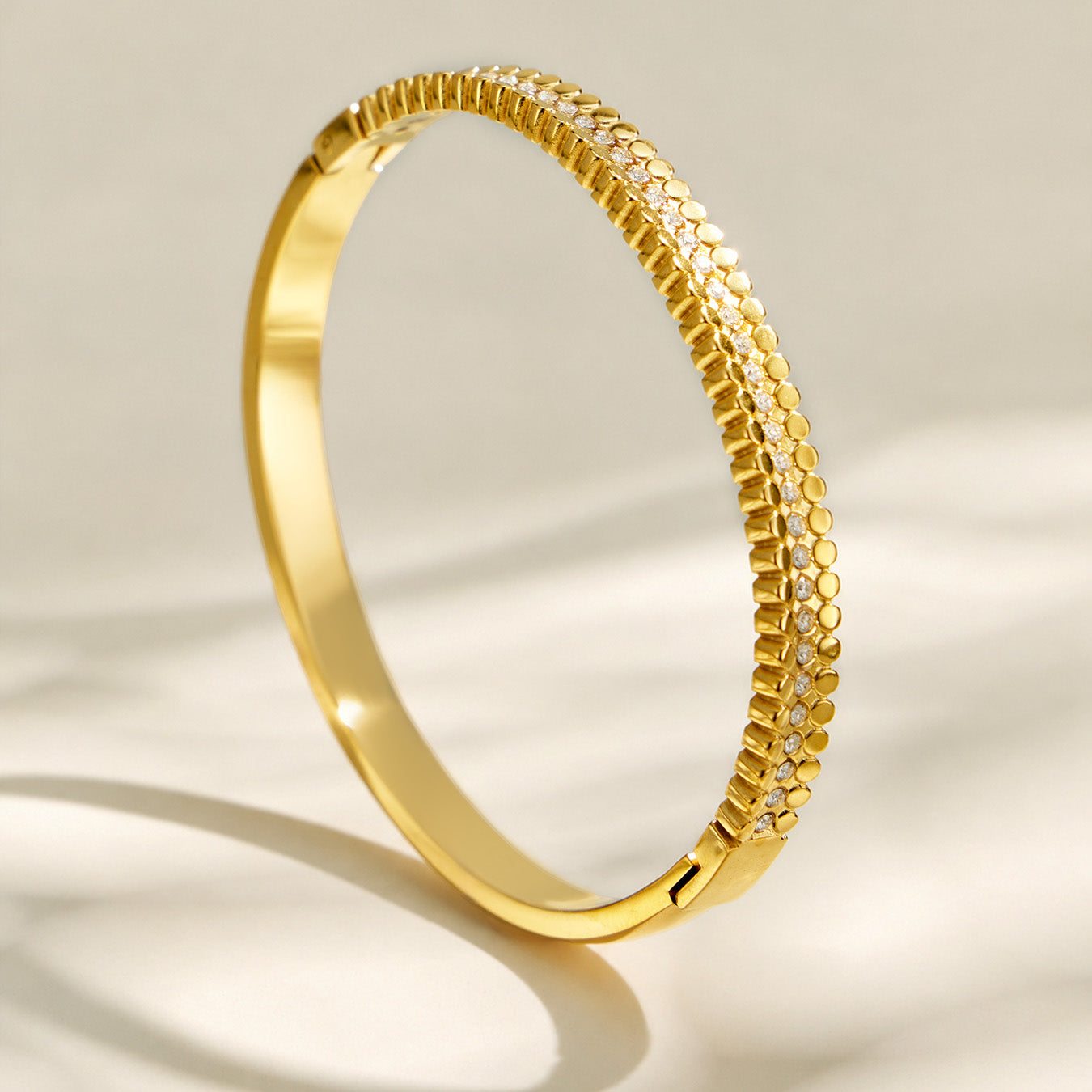 Side view of a slim gold striped bangle with clear cubic zirconia accents