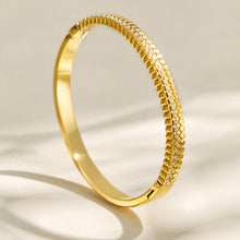 Side view of a slim gold striped bangle with clear cubic zirconia accents