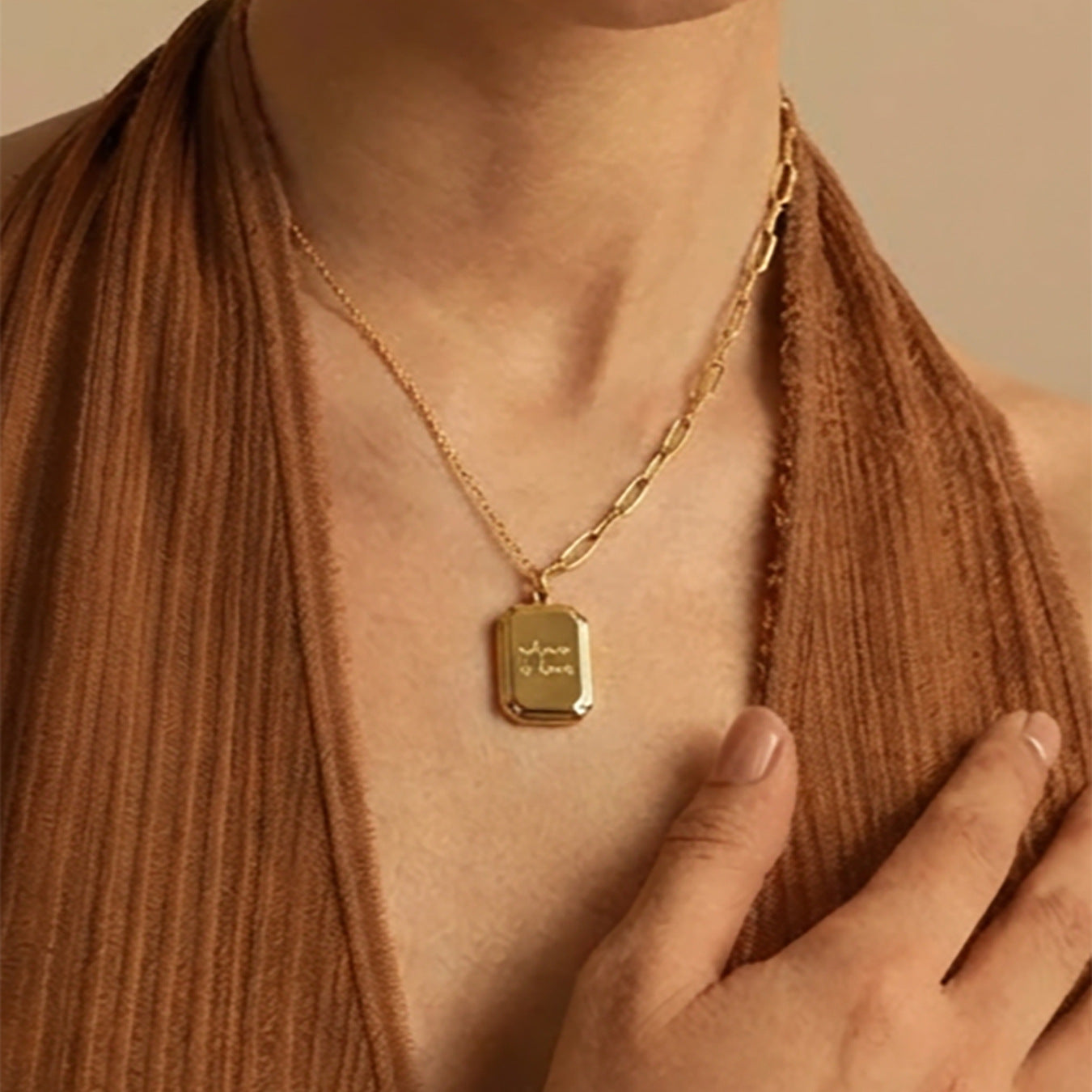 Close-up of polished 18K gold PVD plated "where is love" engraved tag pendant necklace, highlighting the delicate engraving and dual chain construction