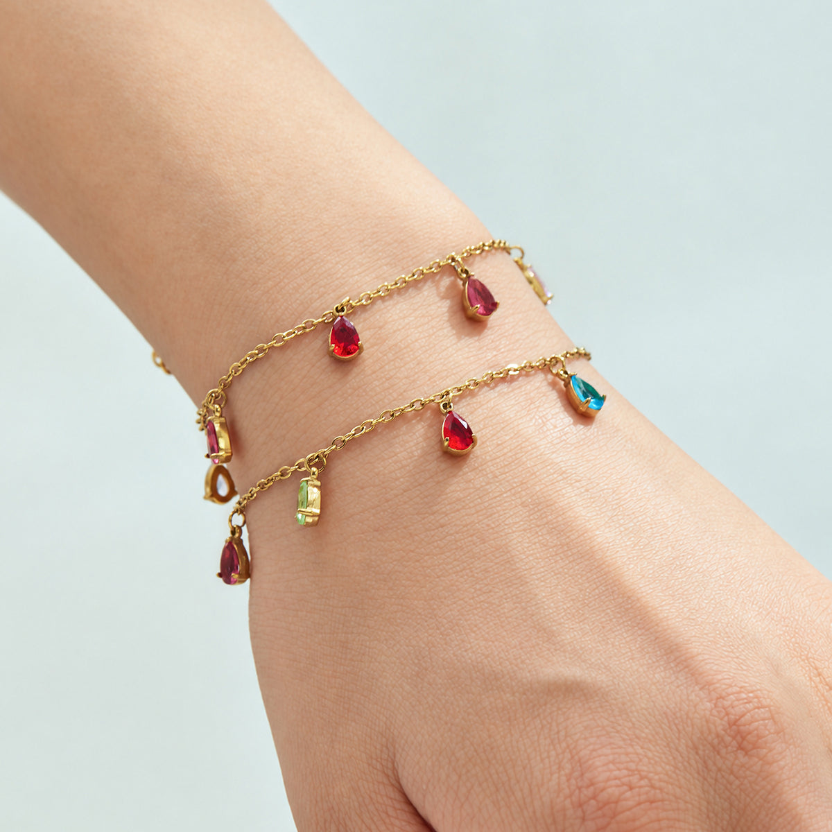Two gold-tone teardrop zircon bracelets layered on the wrist