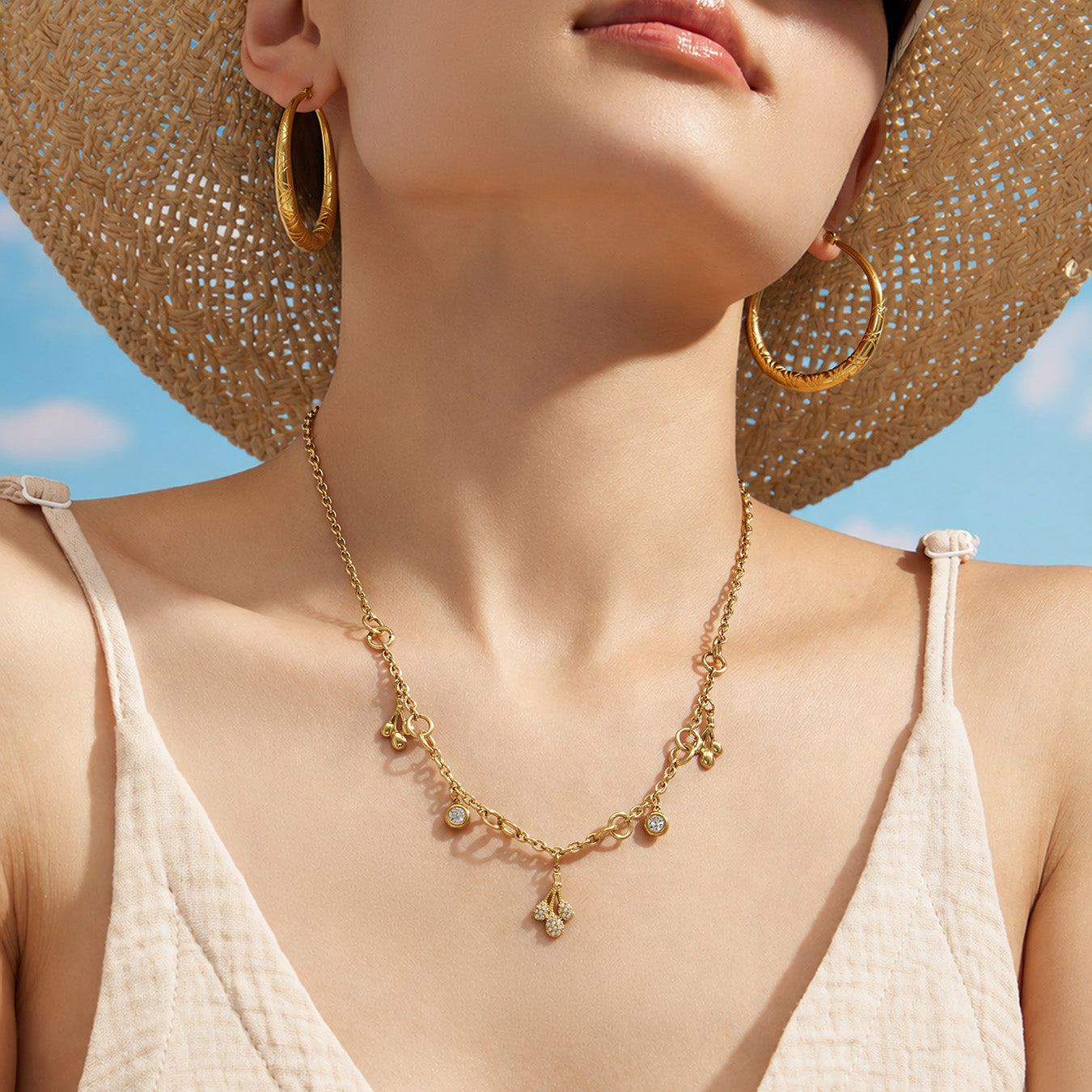 Gold teardrop charm necklace worn by a model in a summer resort setting