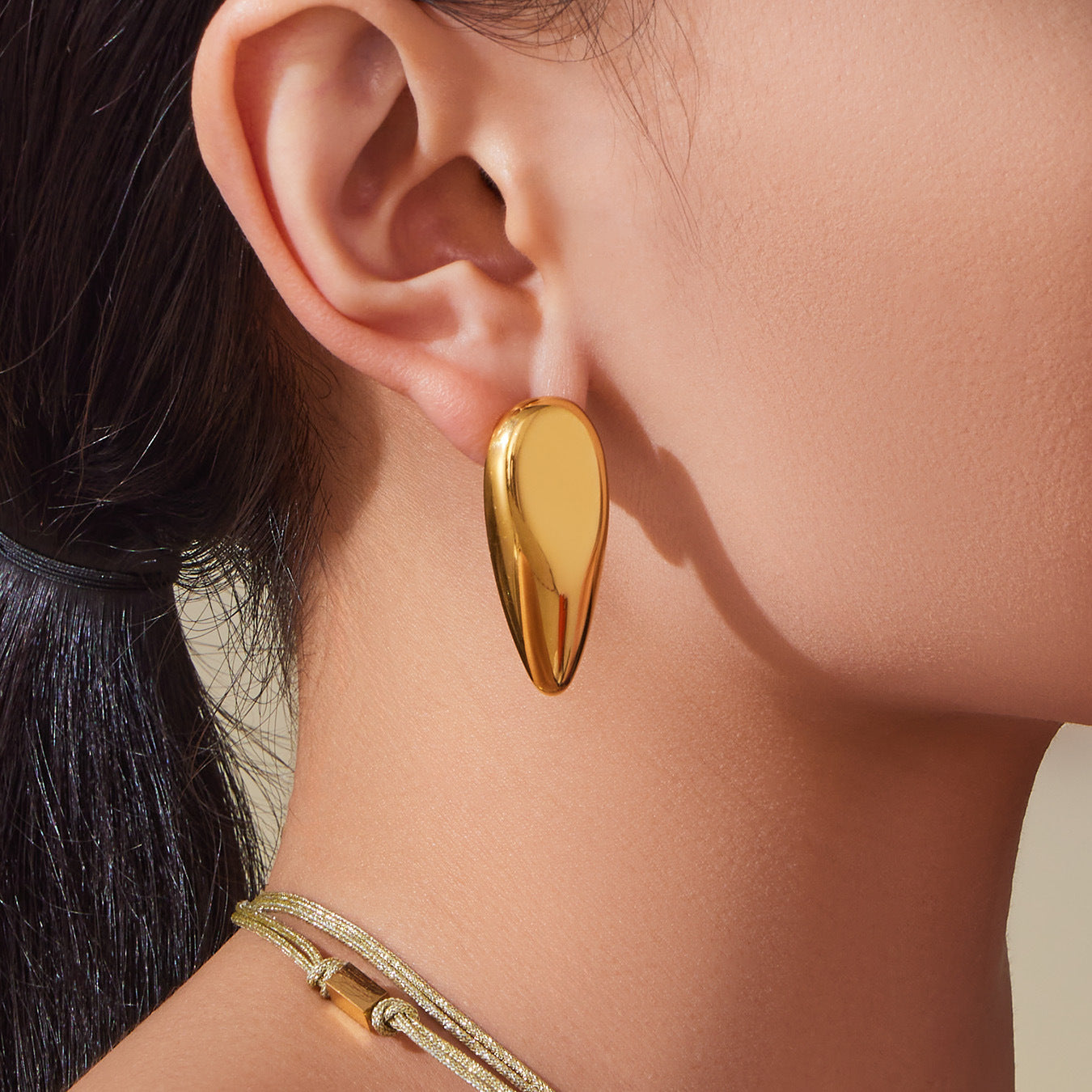 Model wearing gold mirror-finish teardrop stud earrings made of 316L stainless steel, bold statement look