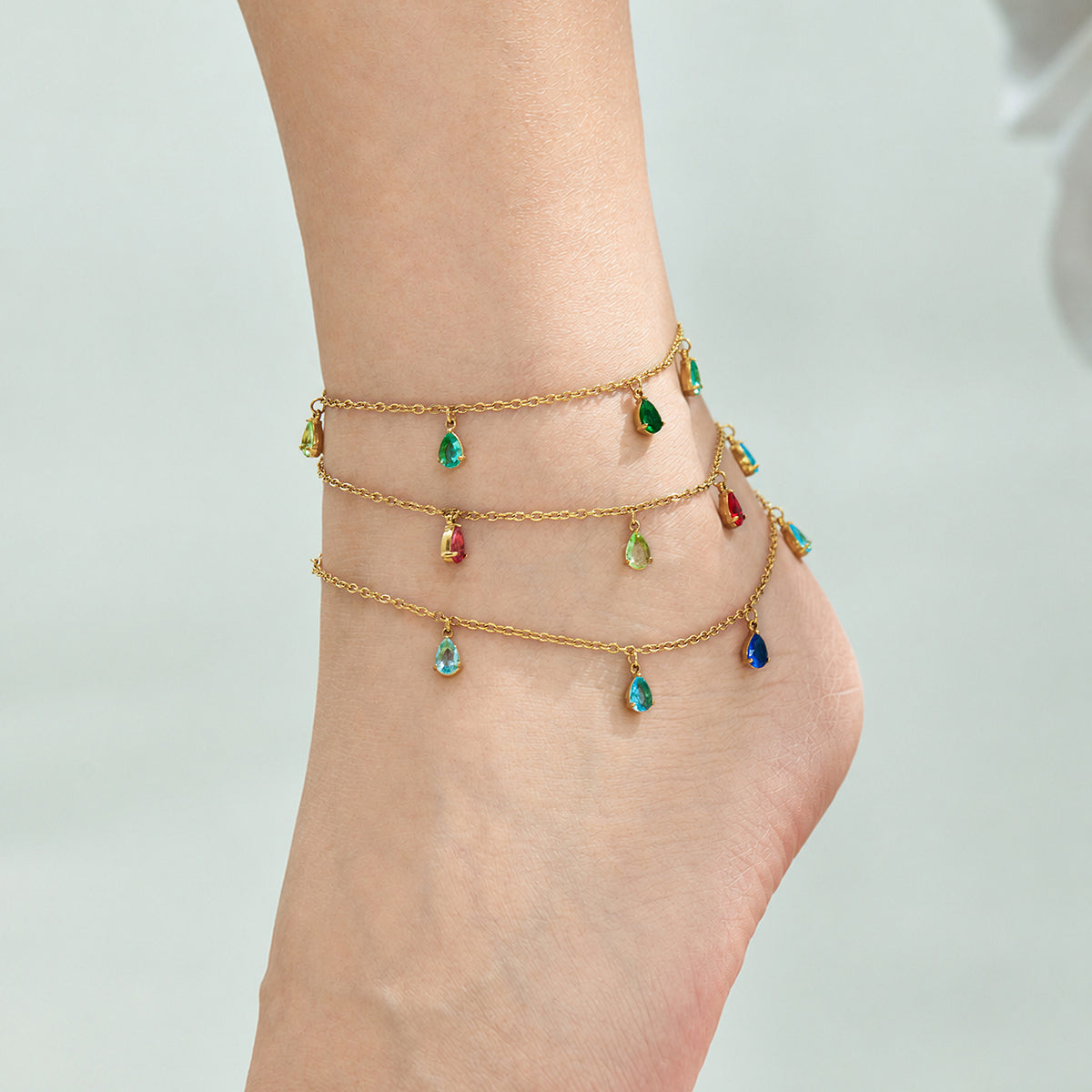 Gold-tone teardrop zircon anklets layered around the ankle