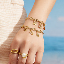 Two gold teardrop zircon charm bracelets layered on a model wrist