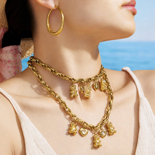 Close-up of a model wearing a gold teddy bear and heart charm necklace