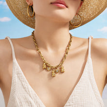 Model wearing a gold teddy bear charm necklace against a blue background