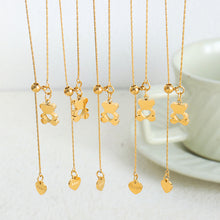 Gold teddy bear pendant necklaces displayed in a row with adjustable hanging chains and heart charms