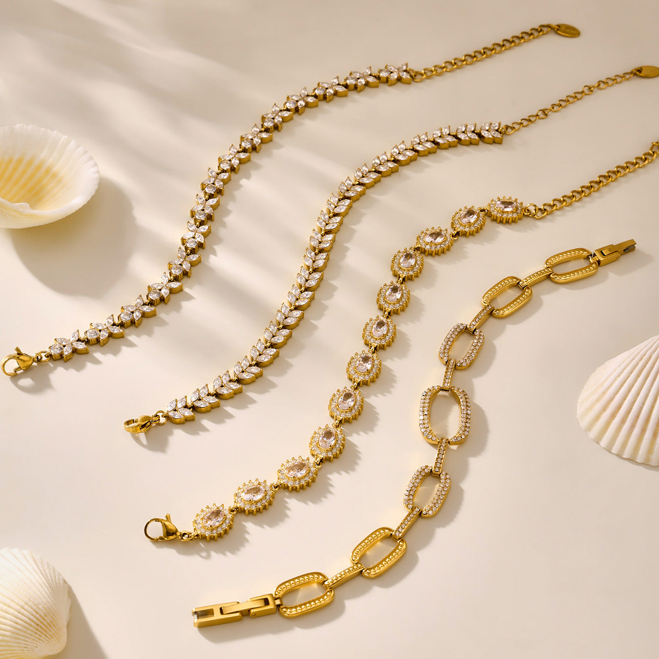 Gold tennis and link bracelets arranged side by side on a neutral background