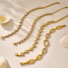 Gold tennis and link bracelets arranged side by side on a neutral background