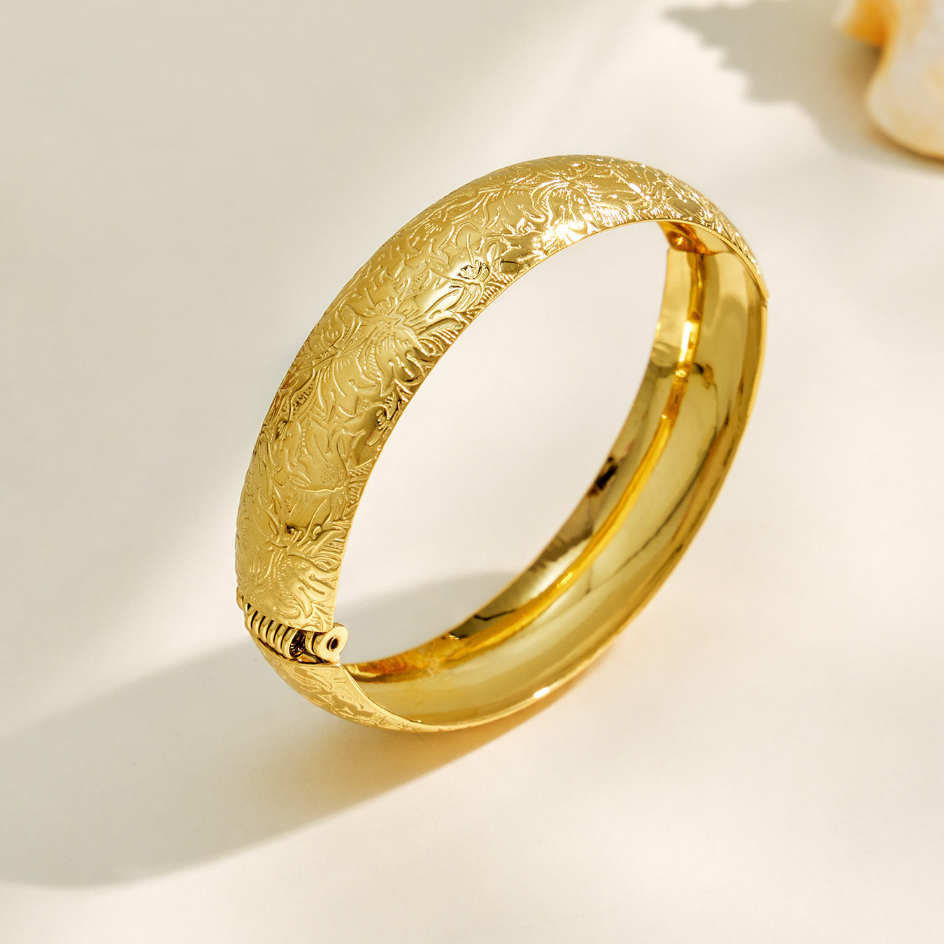 Gold textured wide bangle with engraved floral surface detail