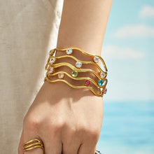 Hand close-up wearing a gold three-layer open bangle