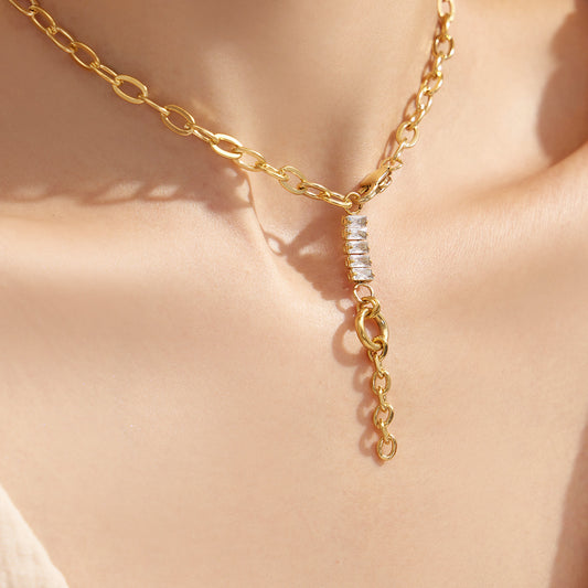 Close-up of a model wearing a gold zircon toggle lariat necklace with a white outfit