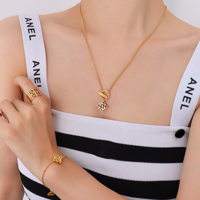 Model wearing a gold-tone toggle pendant necklace with a matching symbol charm bracelet