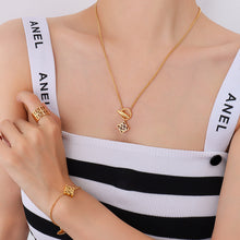 Model wearing a gold-tone toggle pendant necklace with a matching symbol charm bracelet