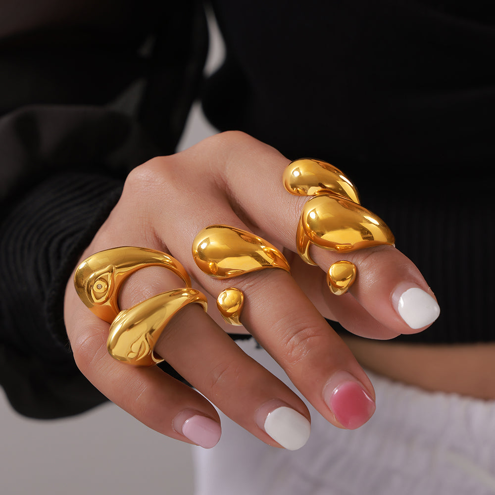 Model wearing gold-tone sculptural open rings and organic cutout rings