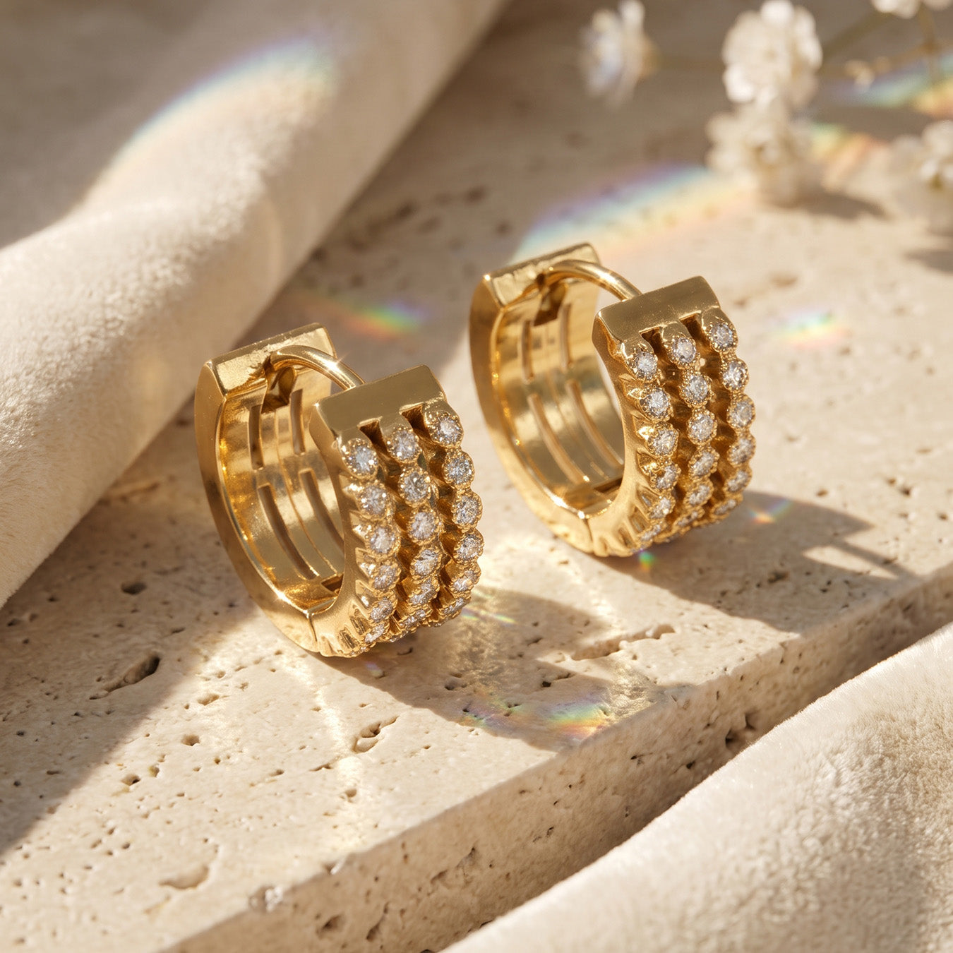 Close-up side view of gold triple-row pavé zircon huggie earrings on stone