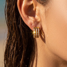 Model with wet dark hair wearing gold triple-row zircon huggie earrings