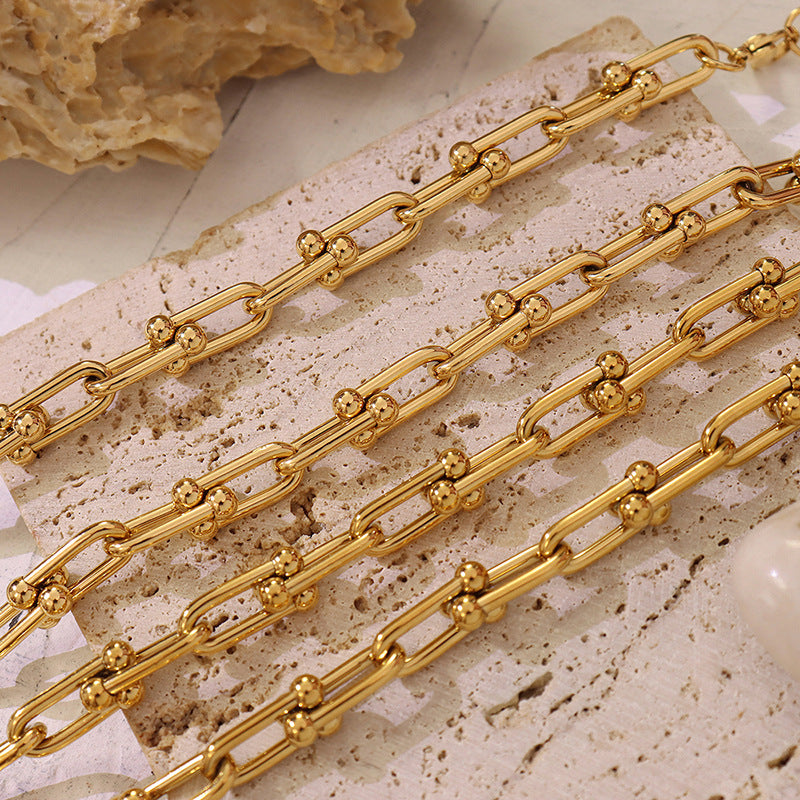 Close-up of gold U-link chain jewelry with elongated polished links