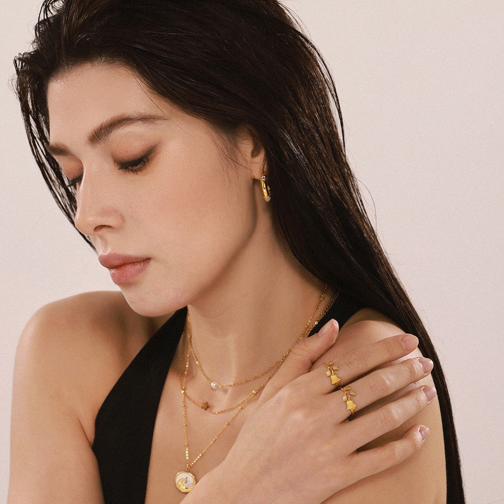 Side-profile model wearing a gold-tone floral open ring with sculptural rose design