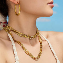 Gold-tone watch band chain necklace layered on model with zircon link details