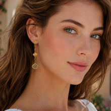 Gold clover drop earrings with white crystal details styled on a model