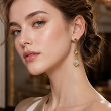 White crystal clover drop earrings in a gold finish shown in a model side view