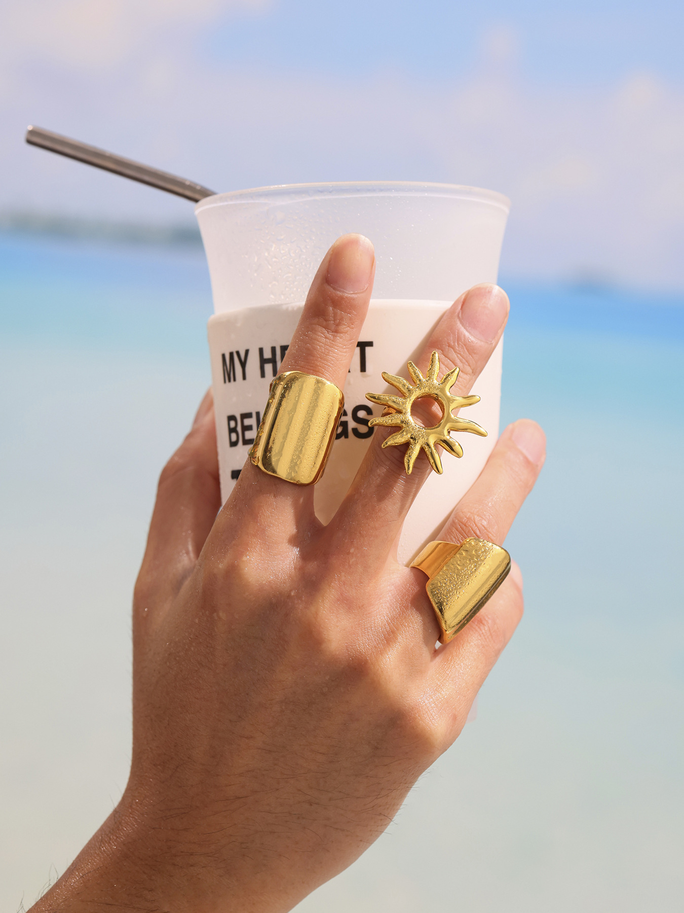 18K PVD gold wide band ring and sunburst ring styled with vacation drink by the sea