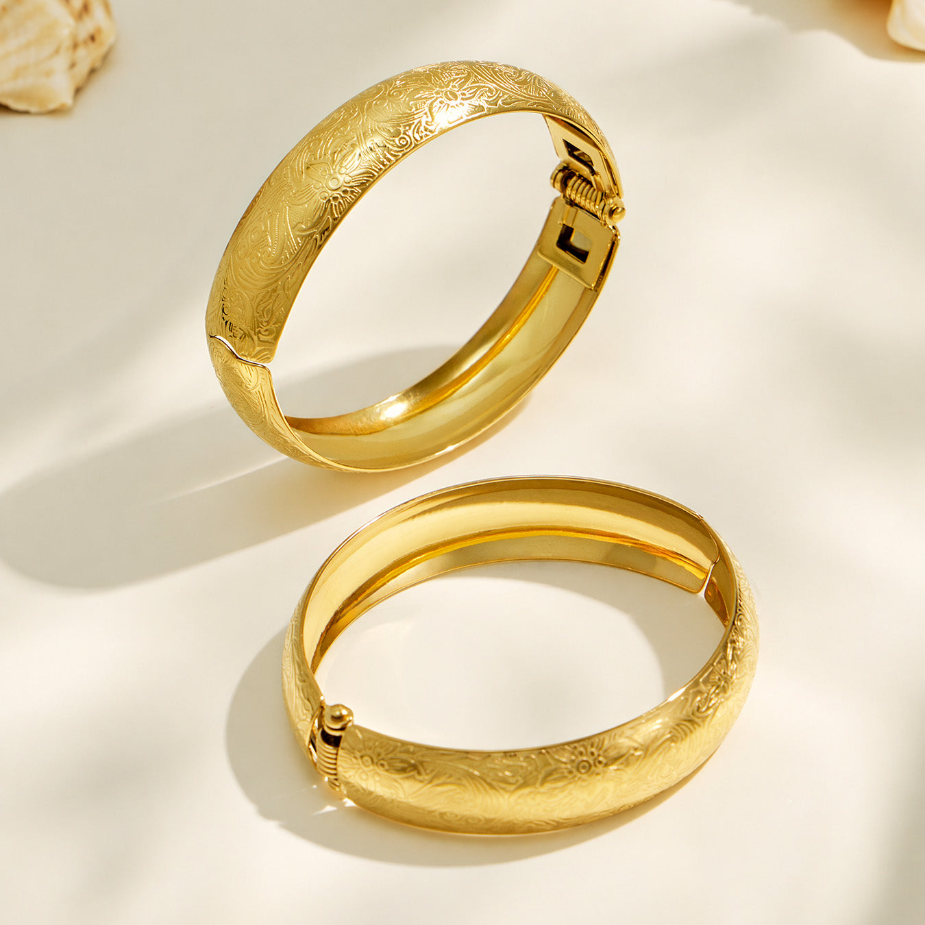 Gold wide floral engraved bangle displayed on a neutral background