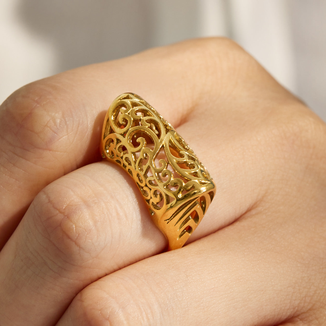 Gold tone wide cage-style 316L stainless steel ring worn on a model hand