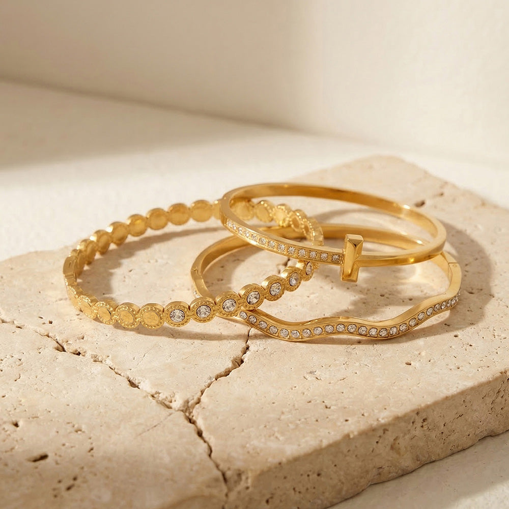Gold and steel tone wavy zircon bangle bracelets in 316L stainless steel displayed on stones for wholesale bracelet buyers