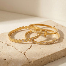 Gold and steel tone wavy zircon bangle bracelets in 316L stainless steel displayed on stones for wholesale bracelet buyers