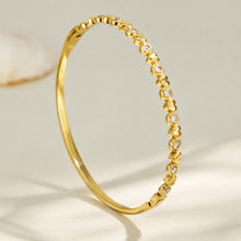 Side profile of a slim gold zircon bangle with a polished geometric edge