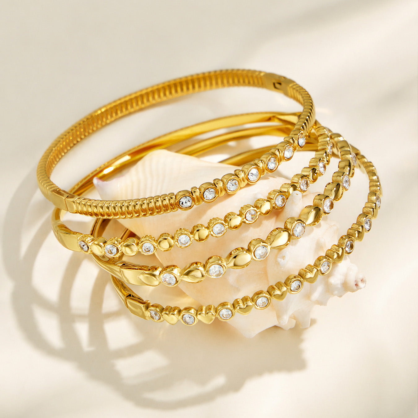 Stacked gold zircon bangles displayed on a neutral background