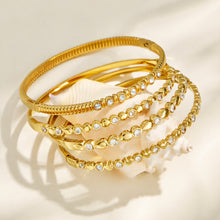 Stacked gold zircon bangles displayed on a neutral background