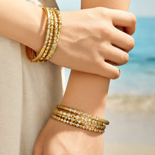 Gold zircon bangles stacked on a model wrist for layered styling