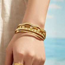 Front view of a model wearing layered gold zircon bangle bracelets