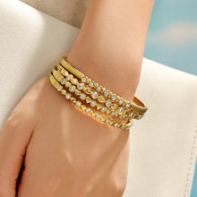 Stacked gold zircon bangles worn on a model wrist near the beach