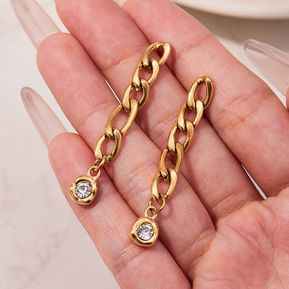 Pair of gold link chain zircon drop earrings displayed in a model hand