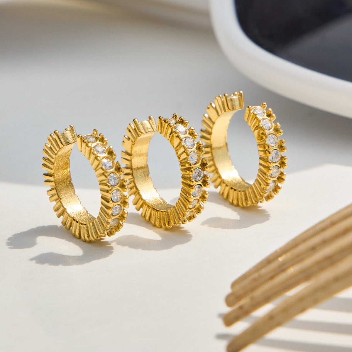 Multiple gold zirconia ear cuffs arranged on a neutral surface to show their circular profiles and stone settings