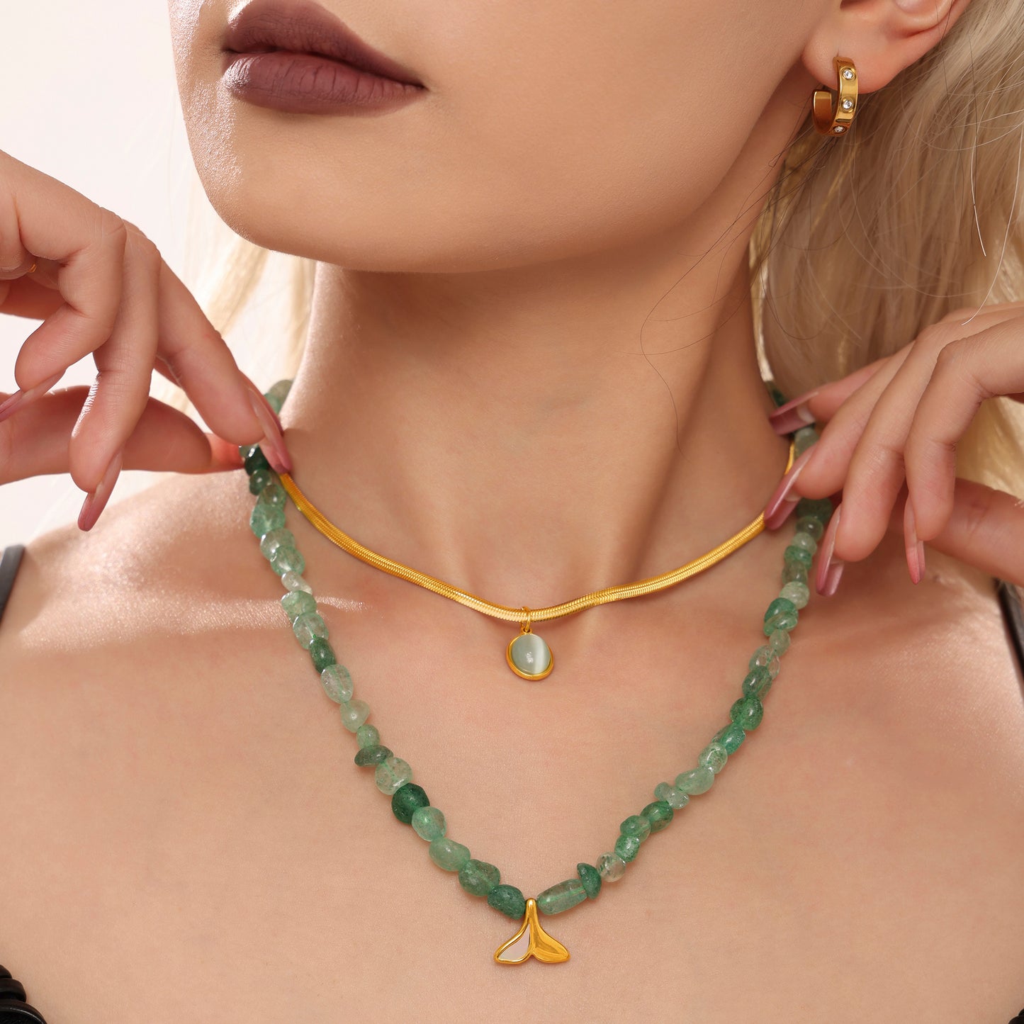 Close-up of a model wearing layered green bead and gold pendant necklaces