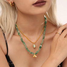 Green beaded and gold chain layered necklace styled with a black top