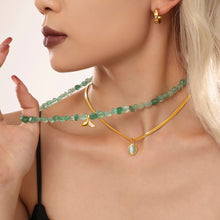 Side profile of a model wearing a green beaded necklace with a layered gold chain