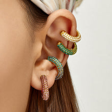 Model wearing a green cubic zirconia C-shaped ear cuff with no piercing required