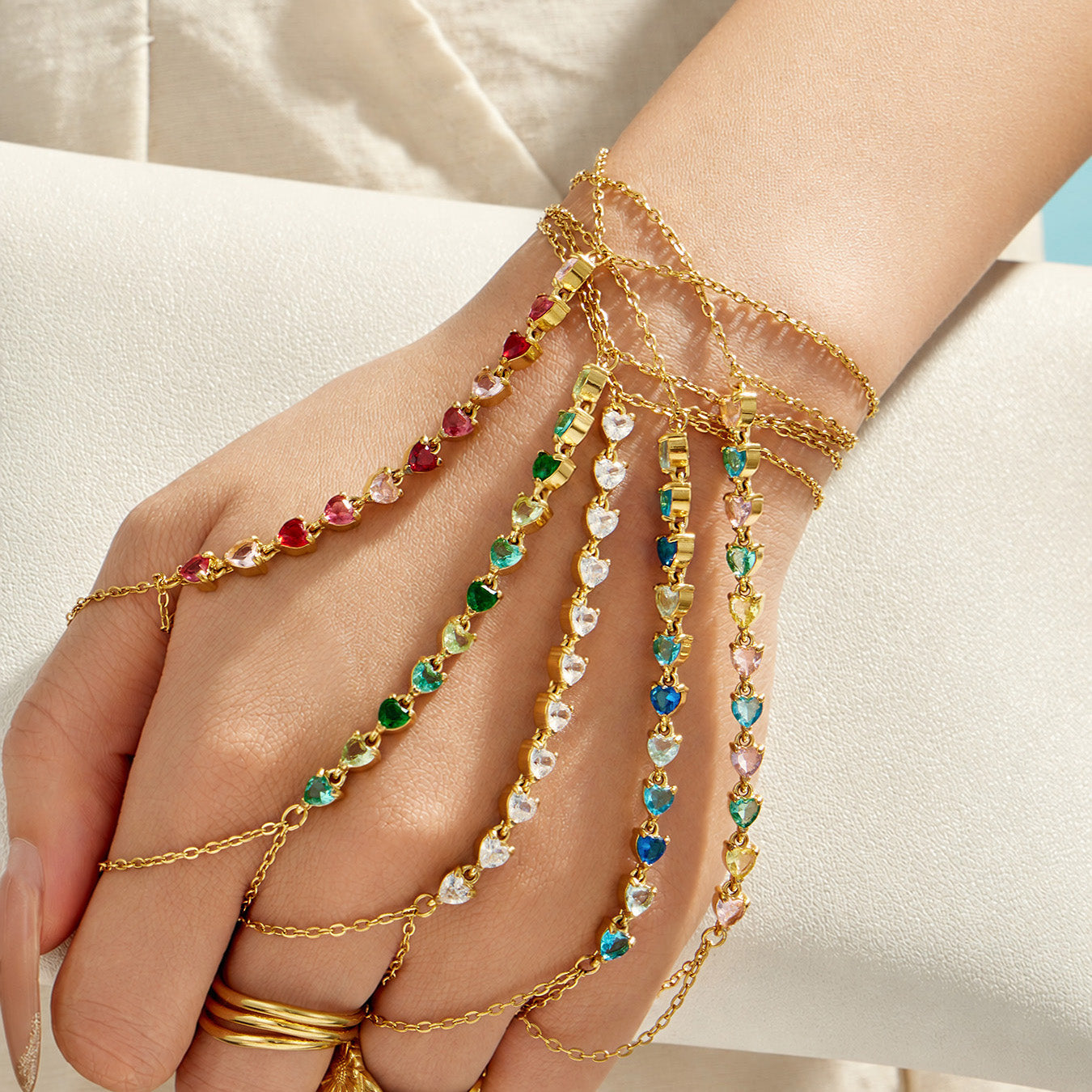 Model wearing a green cubic zirconia hand chain bracelet with gold stainless steel chain