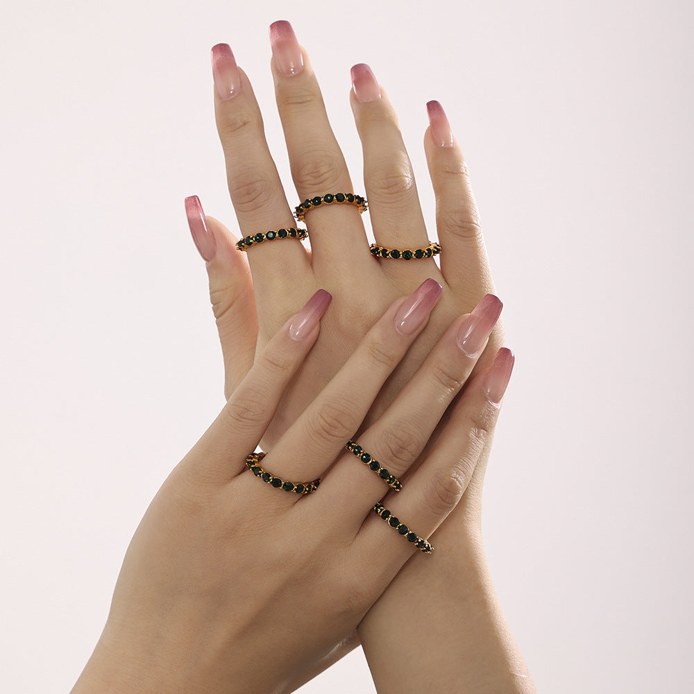 Model wearing a green glass eternity ring with other gold rings on the hand