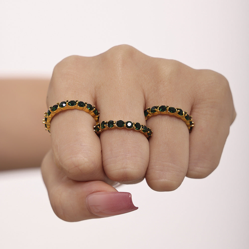 Close-up of green glass eternity rings styled in a layered ring stack