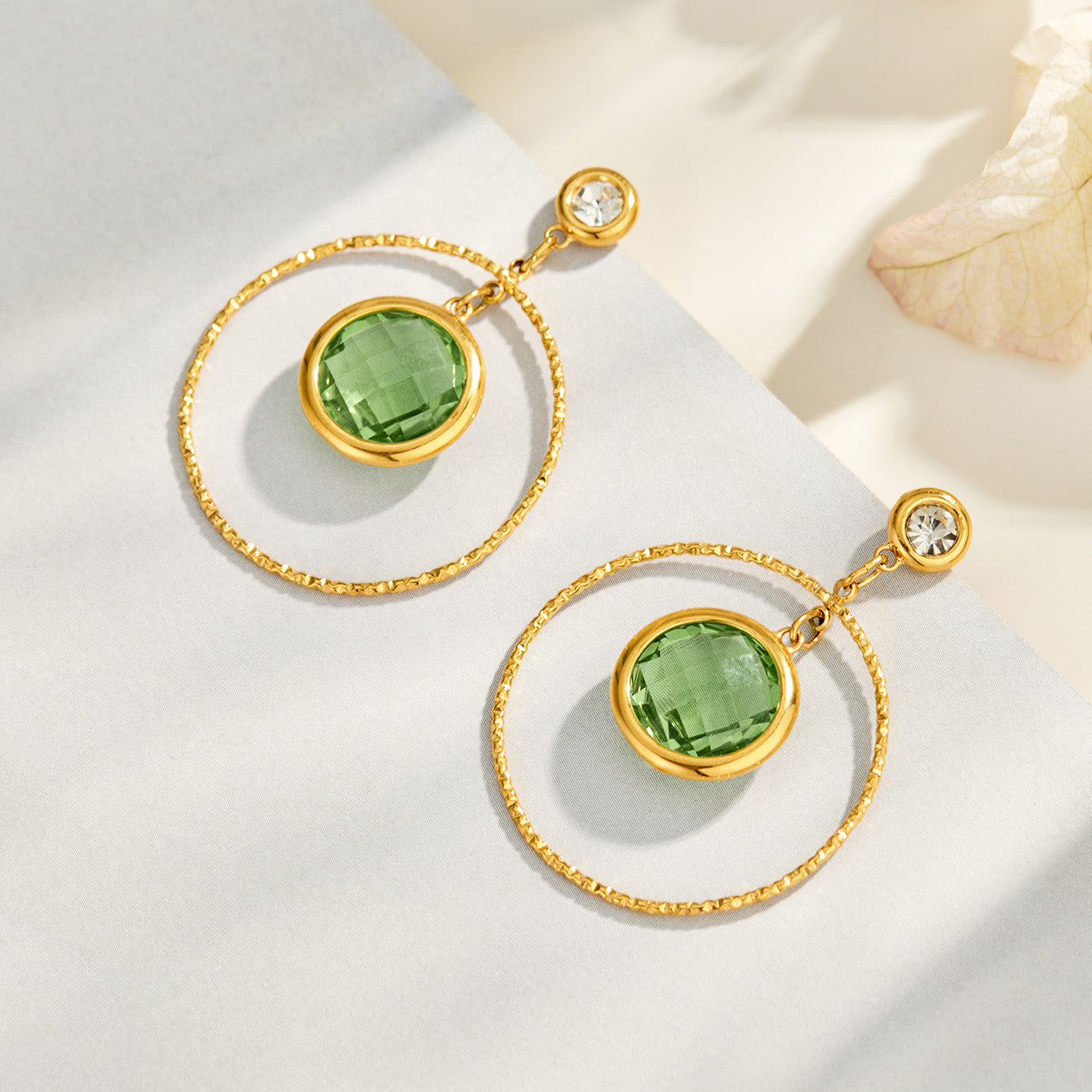 Green glass stone drop earrings displayed on a neutral jewelry background