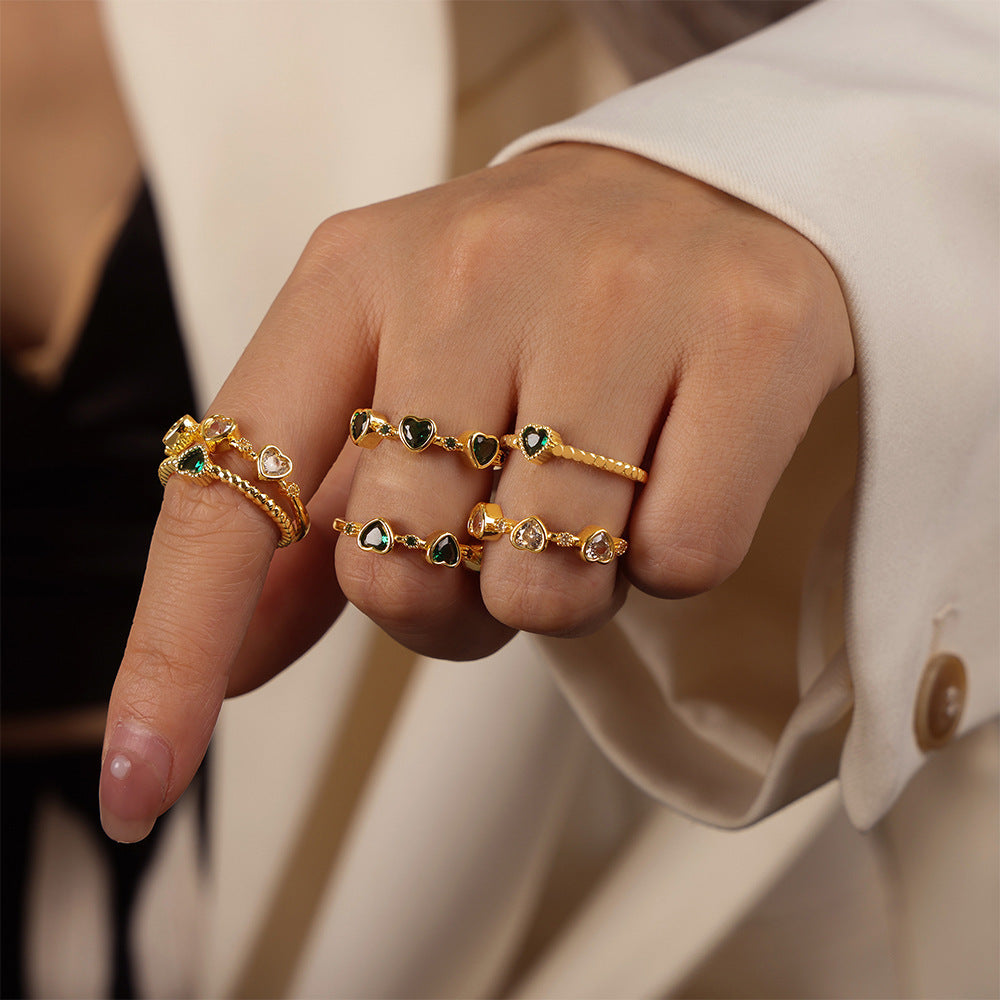 Model wearing multiple green heart zircon stackable rings across three fingers