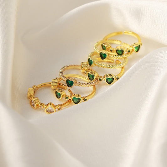 Green heart zircon rings arranged on ivory satin for a boutique jewelry display